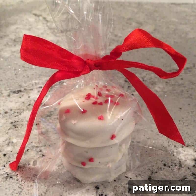 Love-Dipped White Chocolate Oreos 4 White chocolate covered Valentine's Day Oreo cookies with heart sprinkles in a cellophane baggie tied with red ribbon.