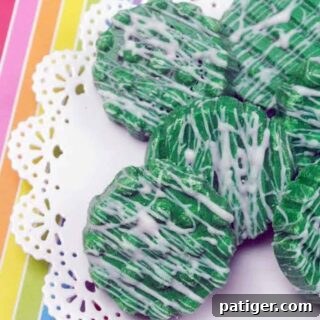 Candy-Dipped Green Oreos with white chocolate drizzle on rainbow background.