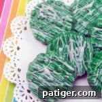 Candy-Dipped Green Oreos with white chocolate drizzle on rainbow background.