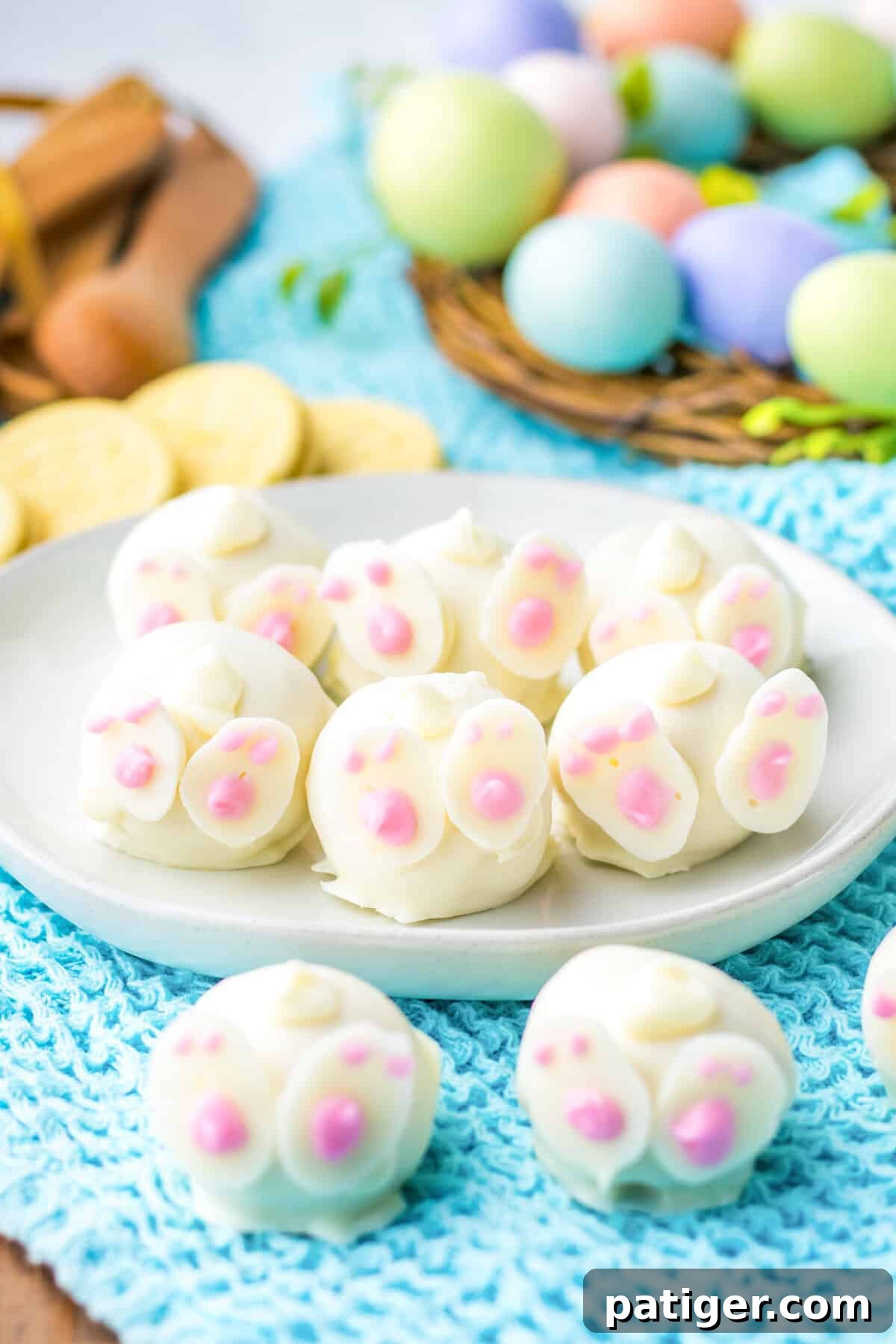 Bunny oreo balls decorated with feet and tails to look like bunny butts. Lemon oreo cookies and easter eggs are in the background.