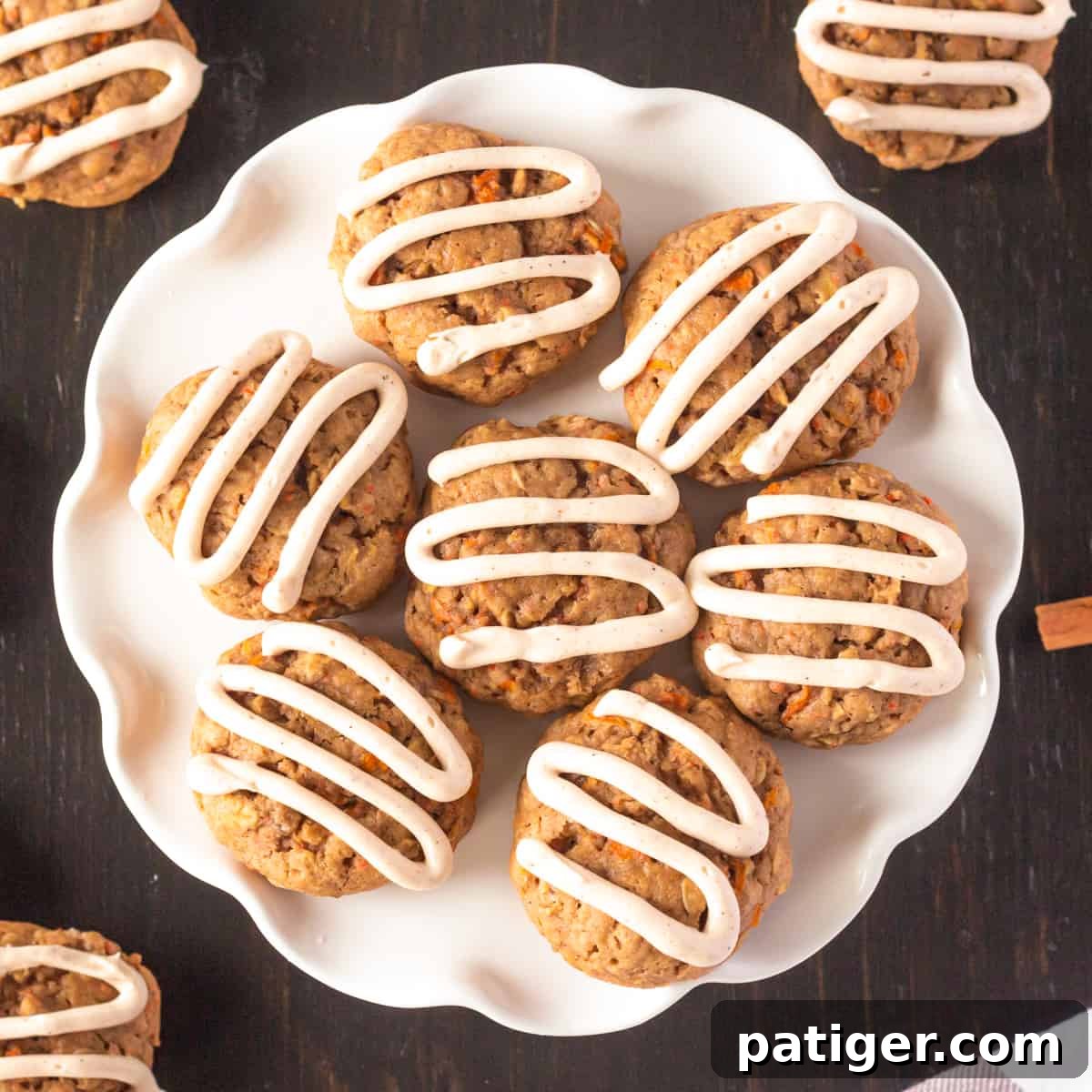 Carrot cake cookies with cream cheese frosting piped on top in zig zag pattern.