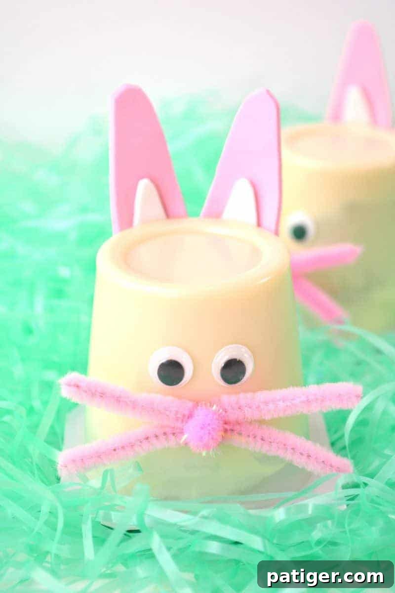 Vanilla pudding cups decorated with pink and white foam ears, googly eyes, a pom-pom nose, and pink pipe cleaner whiskers.