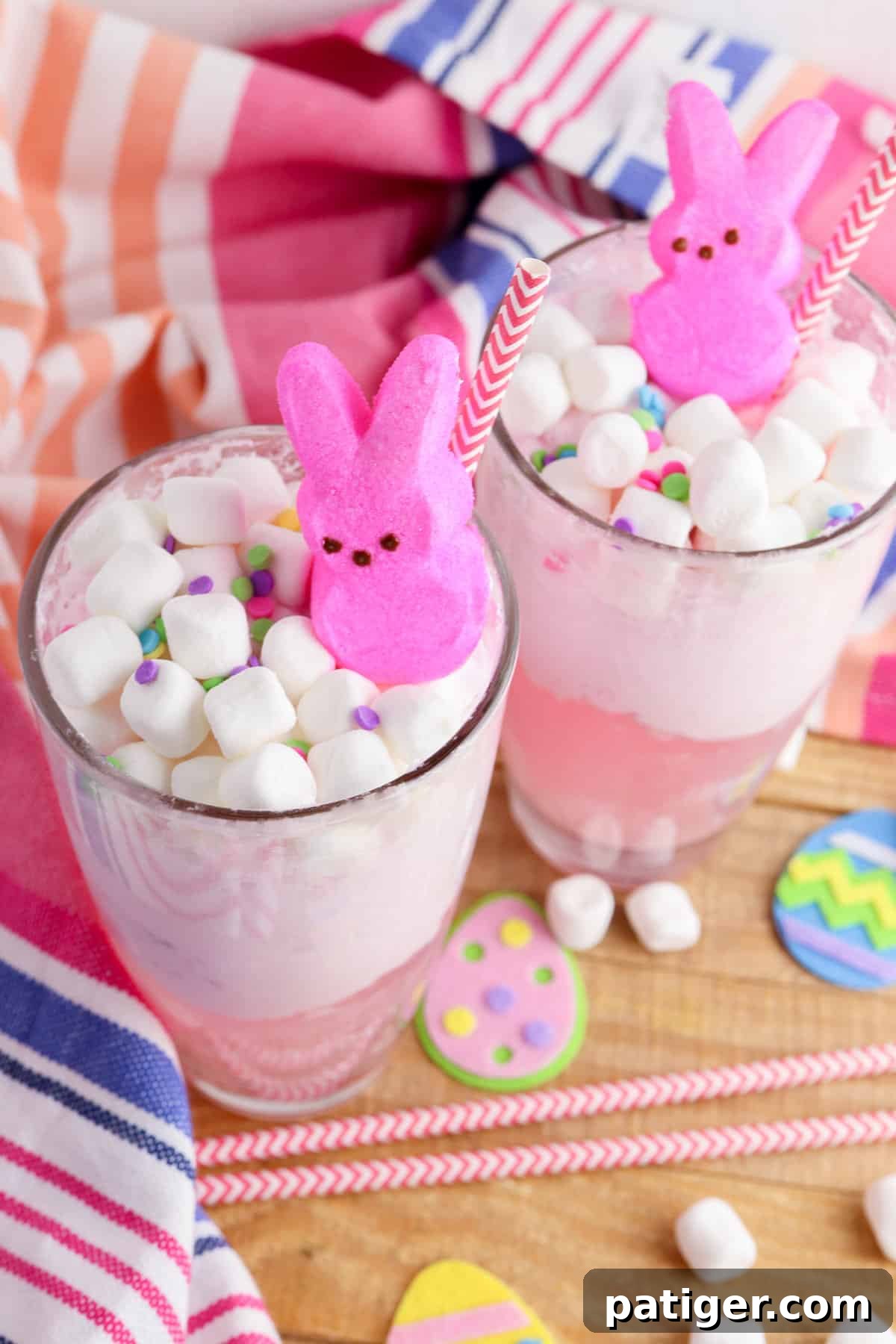 Two glasses with a pink Easter drink topped with marshmallows and peeps.