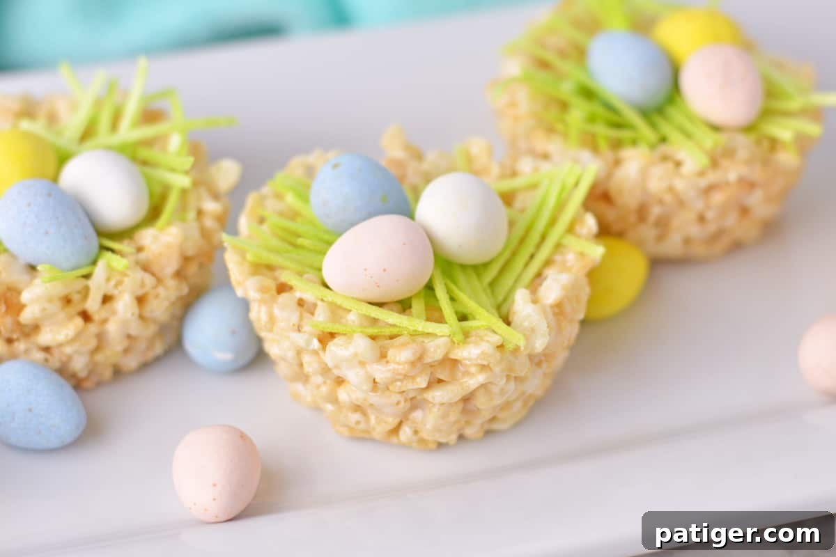 Three rice krispie nests with mini eggs and edible grass.