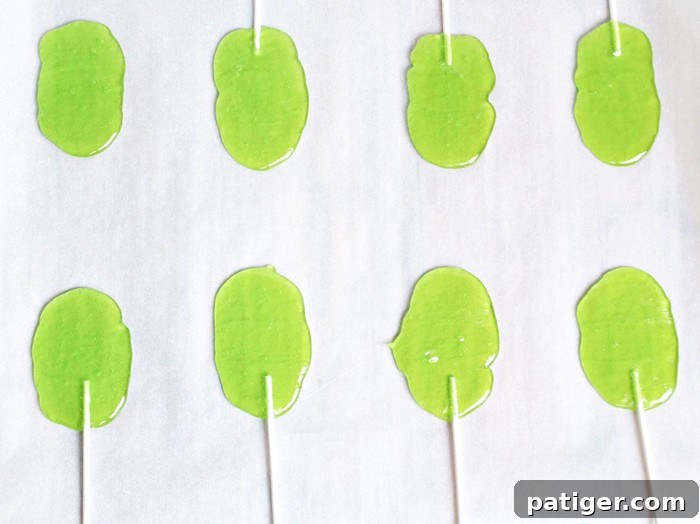 Melted Frankenstein candy lollipops with sticks inserted, ready for decoration.