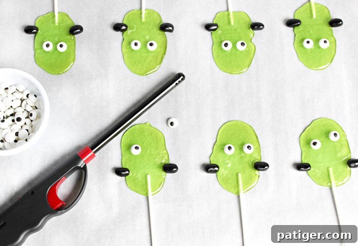 Affixing candy eyes to the Frankenstein Suckers, creating a whimsical and spooky expression.