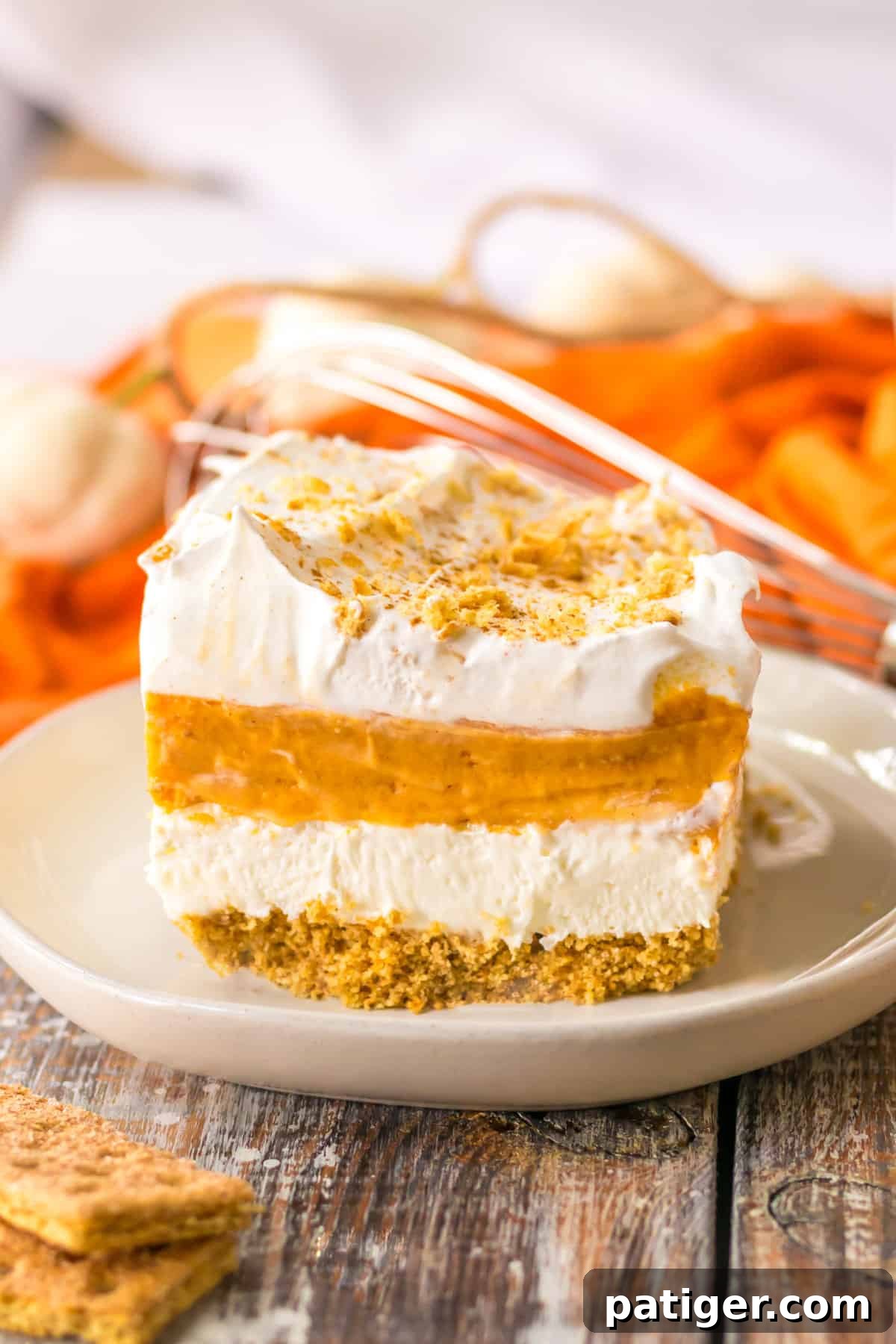 No bake pumpkin lush layered dessert with a graham cracker crust, sweetened cream cheese, pumpkin pie filling, vanilla pudding, and whipped topping.