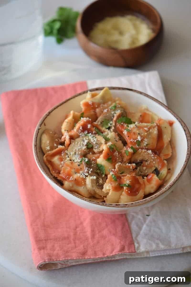 Hearty Mushroom Bolognese 4 Bowl of ravioli with mushroom pasta sauce and bowl of Parmesan chs in the background.