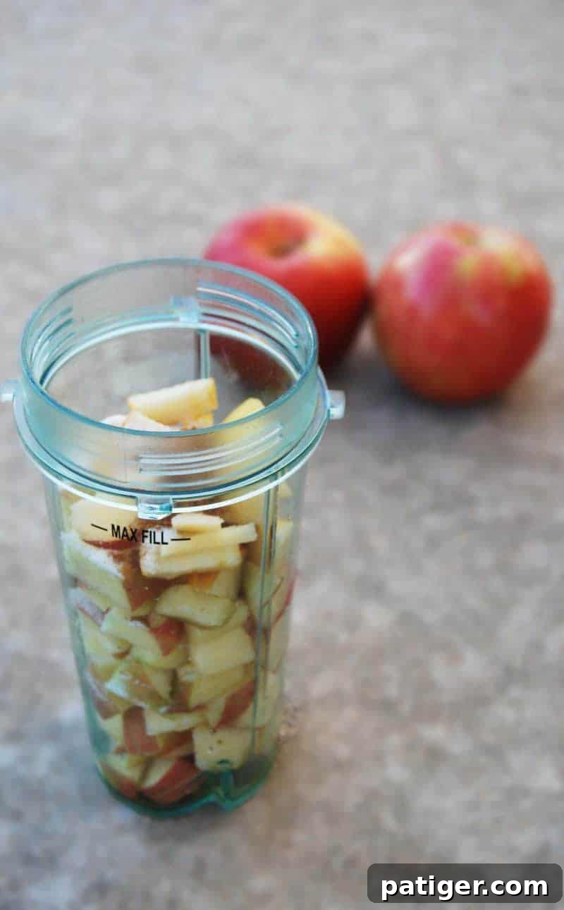Chopped apples in a plastic cup of a blender up to max fill line, ready for blending.