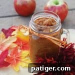 Homemade Applesauce in a jar with a spoon, accompanied by fresh apples.