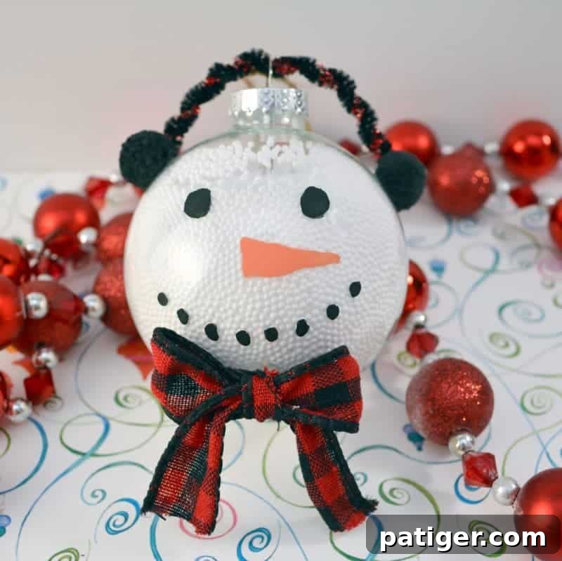 A charming handmade snowman Christmas ornament, created from a clear plastic fillable ball, ideal for a fun kids' craft.