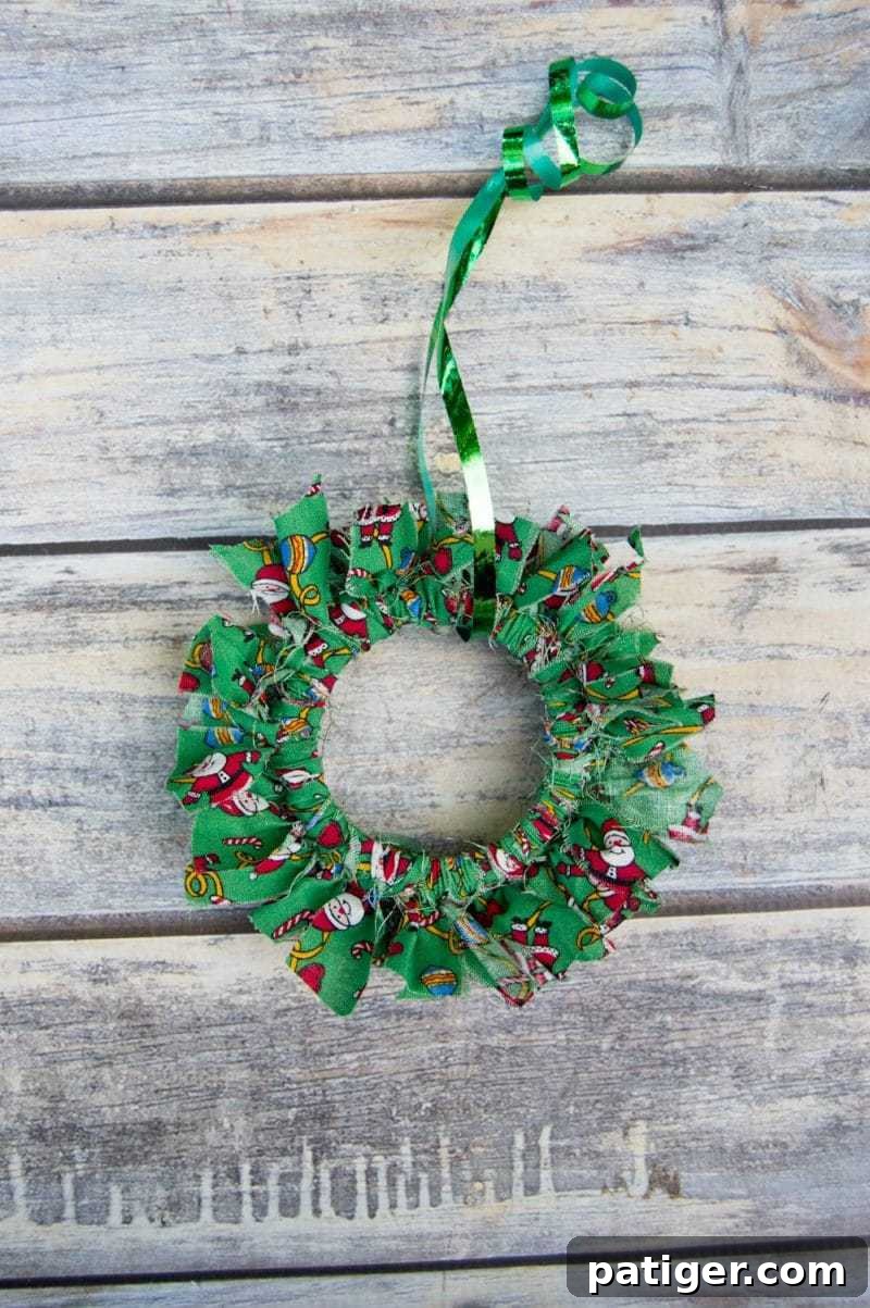 Charming Mason canning jar lid Christmas wreath ornament, adorned with festive fabric strips.