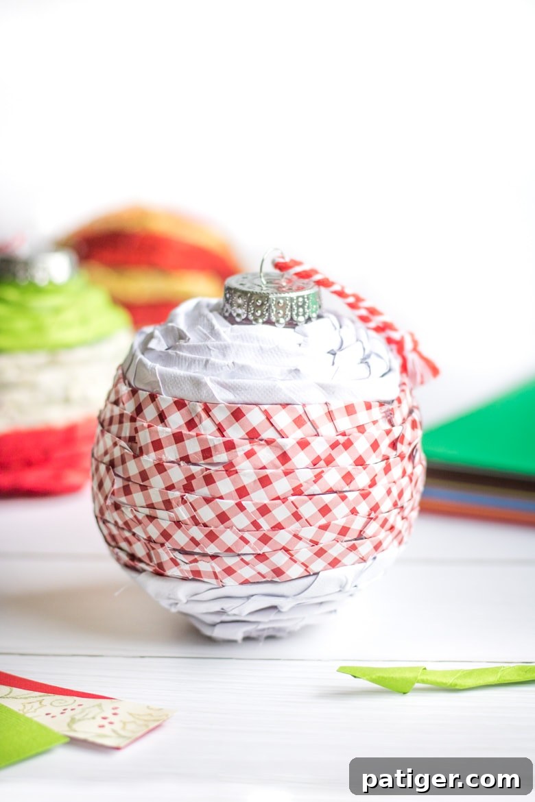 Elegant twisted paper ornament created with clear plastic balls and scrapbook paper, perfect for customized Christmas tree decor.