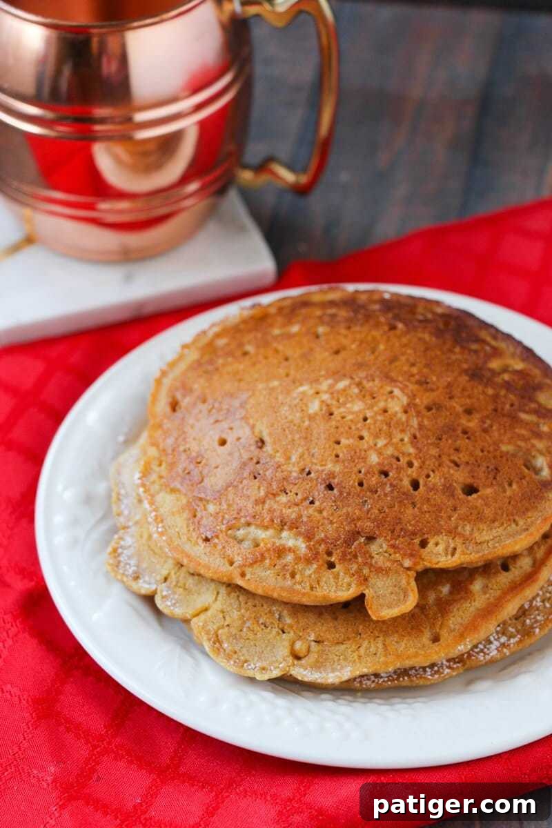 A stack of golden-brown gingerbread pancakes neatly arranged on a white plate, ready to be served.