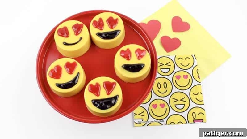 Five finished heart eye emoji oreos arranged on a red plate next to an emoji plush and yellow napkins.