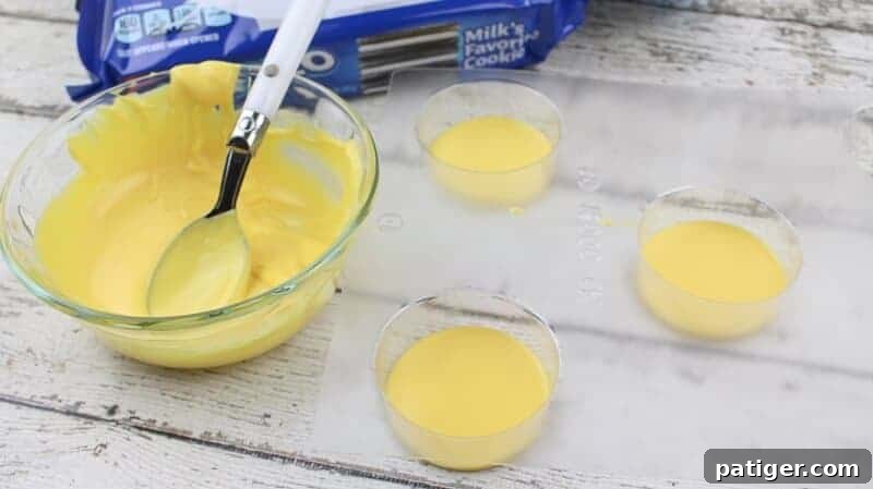 Chocolate covered oreo mold with yellow melted candy in it, ready for the cookie.