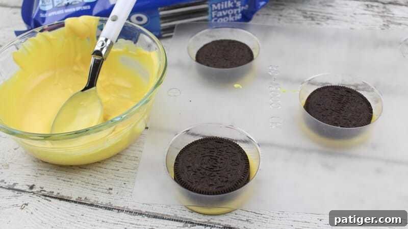 Oreo cookies placed on top of yellow candy in mold, ready for top coating.