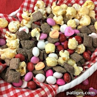 Valentine's Day snack mix made with cherry muddy buddies, popcorn, and candies.