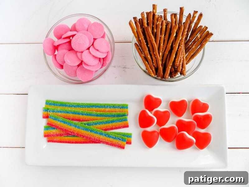 Candy arrow ingredients: pink candy melts, pretzel sticks, rainbow candy, and heart candy.