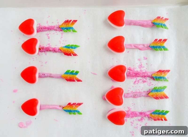 Completed candy arrows on lined baking sheet, some with pink sanding sugar sprinkled onto body of arrow and some without.