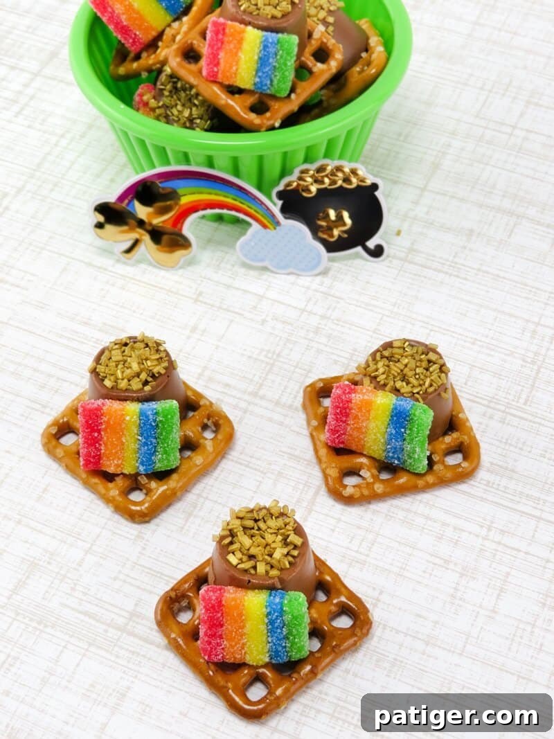 Three perfectly decorated Pot of Gold Pretzels displayed on a tabletop, with a bowl of more finished pretzels blurred in the background, ready for a St. Patrick's Day celebration.
