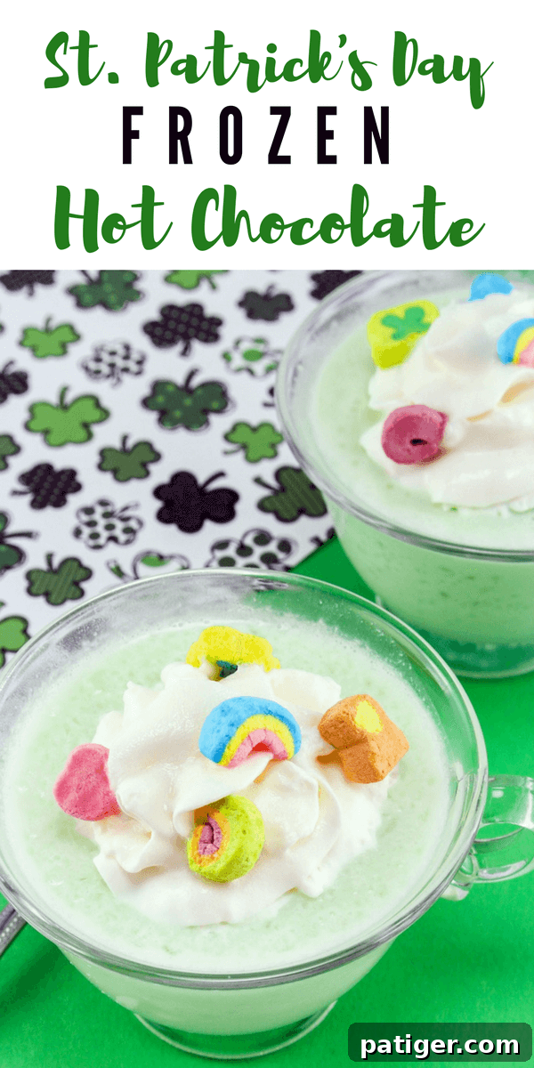 Shamrock Swirl Frozen Hot Chocolate 4 A festive green frozen drink in a clear glass mug, generously topped with an abundant swirl of whipped cream and a sprinkle of Lucky Charms marshmallows, showcasing its delightful texture and vibrant color.