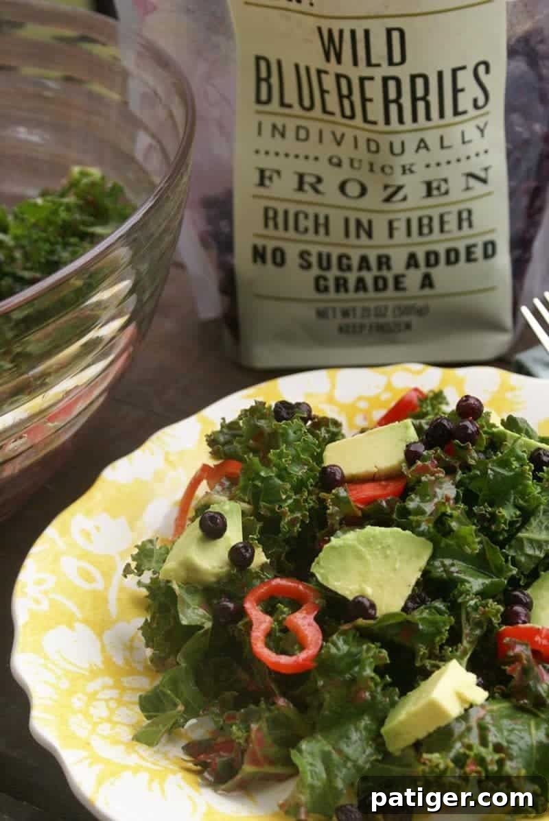 Vibrant Kale Blueberry Salad 3 Close-up of Kale Blueberry Salad, showcasing fresh kale leaves, juicy blueberries, thinly sliced red chili peppers, and creamy avocado slices.