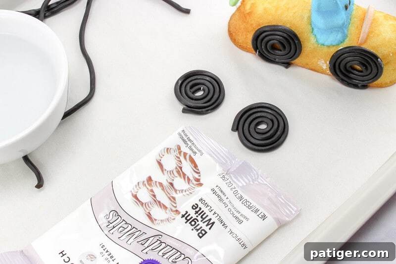 Black licorice string being rolled up to form wheels.