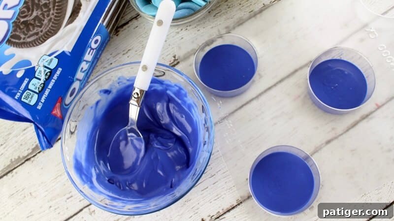 Father's Day Dipped Oreo Delights 4 Melted royal blue candy melts are carefully poured into the bottom of three chocolate cookie molds, ready for the Oreo cookies.