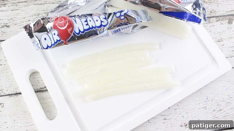 Father's Day Dipped Oreo Delights 8 White Airhead candy strips, 1.5 inches long, neatly cut and arranged on a cutting board for crafting the collars of the Father's Day Oreo ties.