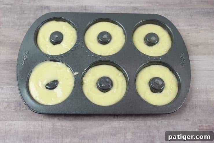 Cake batter in donut pan, ready for baking into Halloween treats.