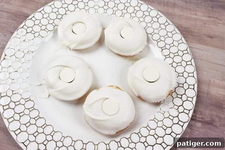 White coated doughnuts with white candy covering the hole in center, forming the pupil's base.