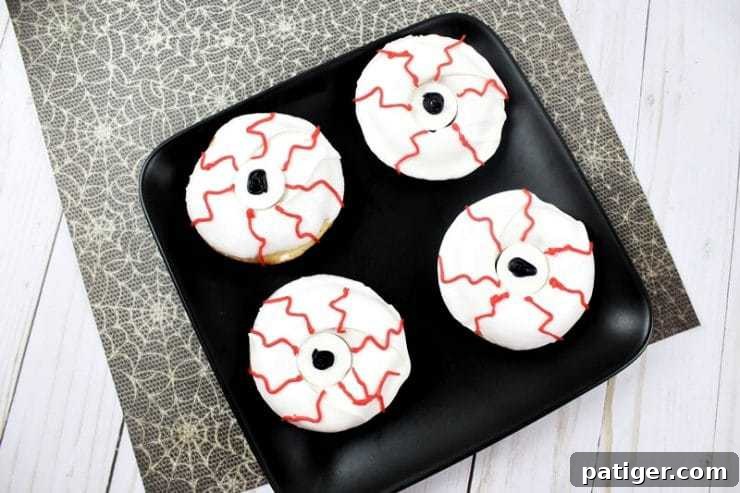 Finished monster eyeball bloodshot donuts on black plate, a perfect creepy Halloween treat.