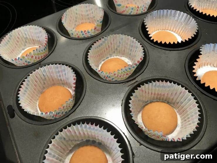 Vanilla Wafer Banana Pudding Cupcakes 3 A cupcake tin precisely lined with cupcake liners, each containing a single Nilla wafer resting at the center of its base, ready to be filled with batter.