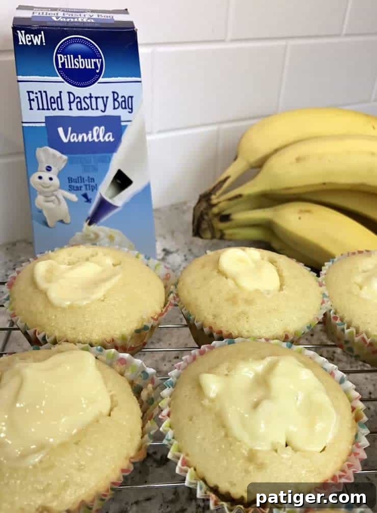Vanilla Wafer Banana Pudding Cupcakes 5 Expertly cored vanilla cupcakes being filled to the brim with creamy, homemade banana pudding, with fresh banana slices subtly blurred in the background, adding to the allure.