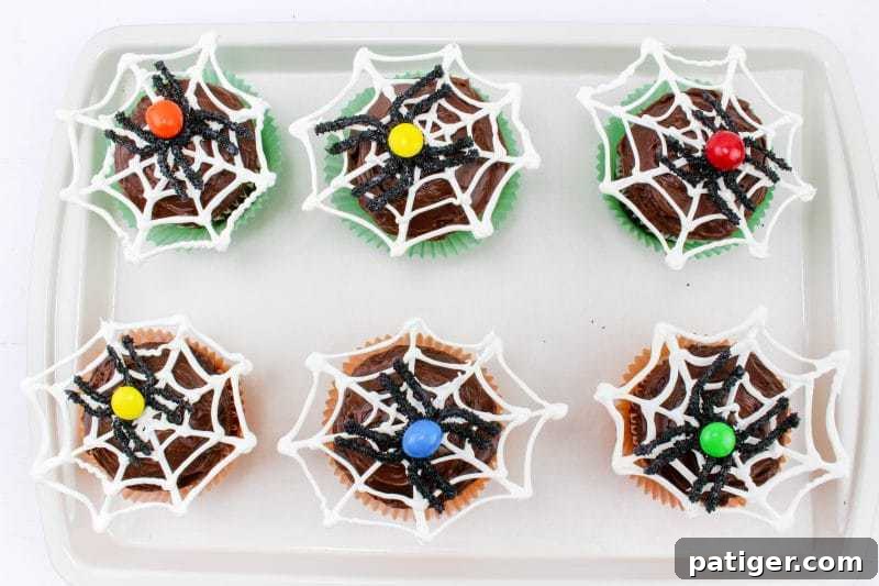 Spider web cupcakes on baking sheet.