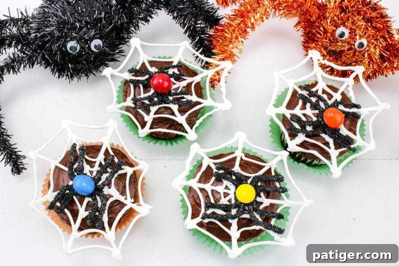 Spider web cupcakes next to two spider decorations.