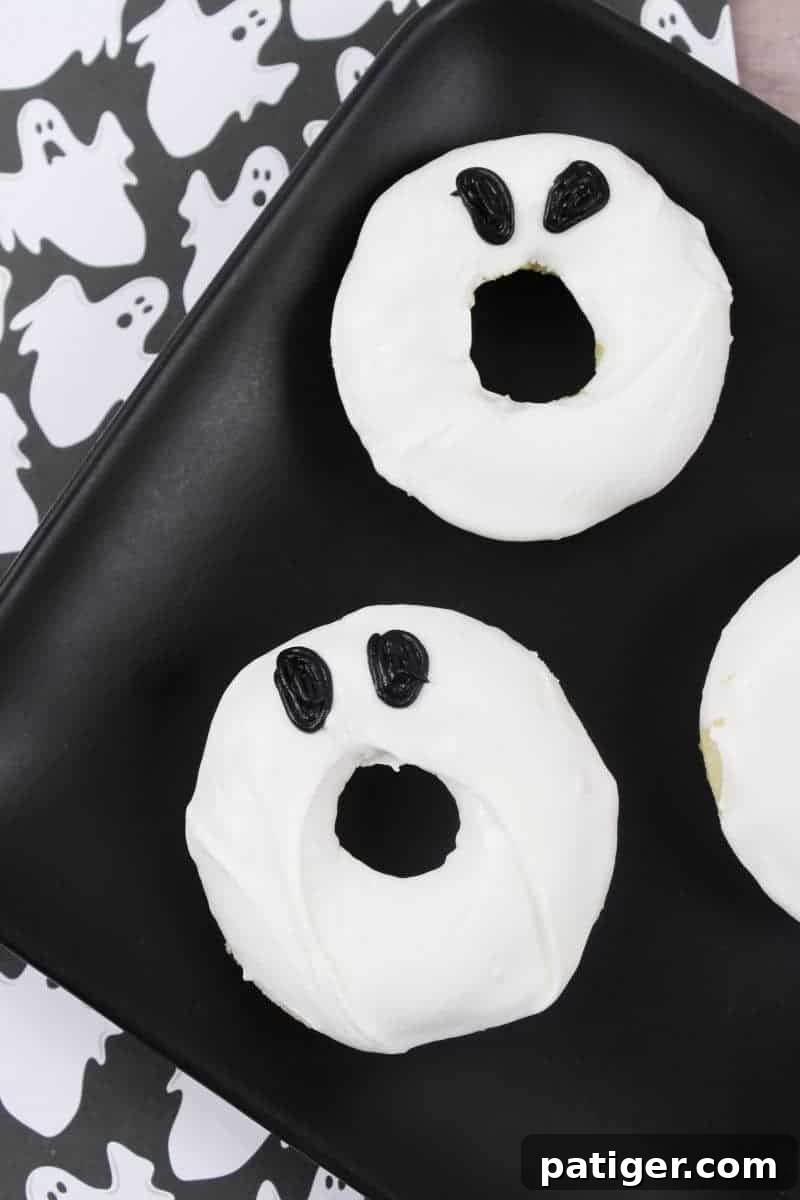 Adorable white ghost doughnuts with black icing eyes, perfect for a quick and easy Halloween treat. A festive and fun dessert or breakfast.