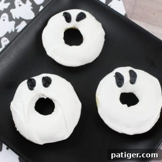 A single ghost doughnut with black eyes, presented on a white plate, symbolizing the easy Halloween treat.