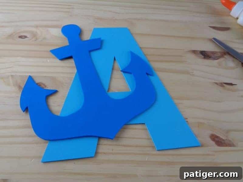 A is for Anchor: Printable Letter A Craft Fun 9 Gluing the dark blue craft foam anchor onto the yellow craft foam letter A, assembling the main components of the 'A is for Anchor' craft.
