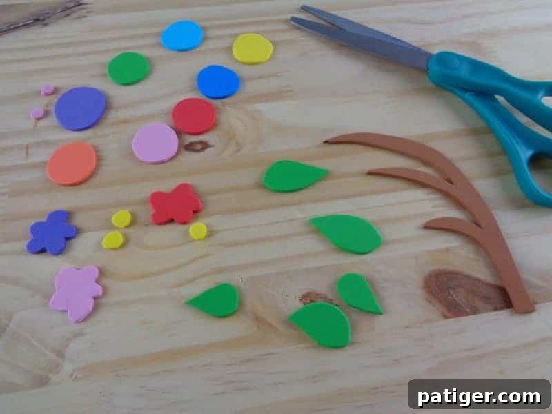 Various craft foam pieces, including the letter C, caterpillar head, body circles, branch, and leaves, are laid out, ready for assembly.