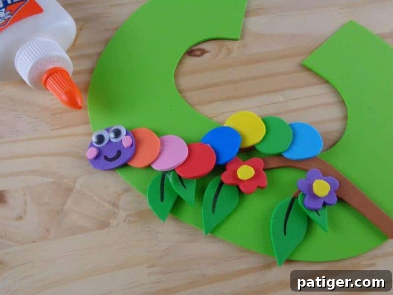 Colorful flower shapes cut from craft foam are glued onto the tree branch, adding decorative elements to the letter C craft.