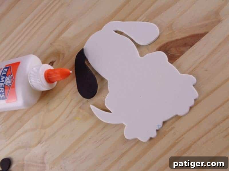 Fun Letter D Dog Craft Printable 7 Step 6: Glue the black ear onto the dog's head, trimming excess for a neat finish.