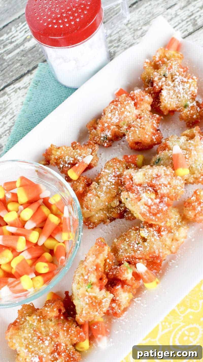 Candy corn fritters presented with a bowl of candy corn and a confectioners sugar duster.