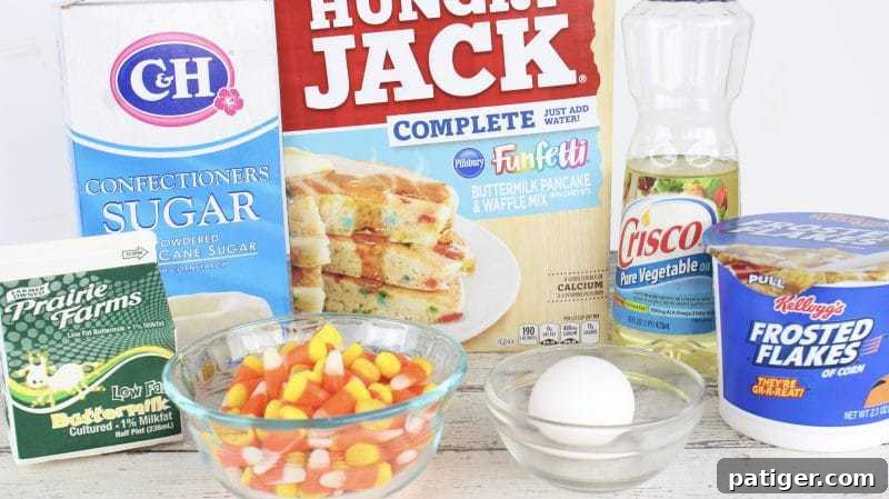 Arrangement of confectioners sugar, buttermilk, candy corn, egg, vegetable oil, Frosted Flakes, and a box of Hungry Jack Funfetti pancake mix.