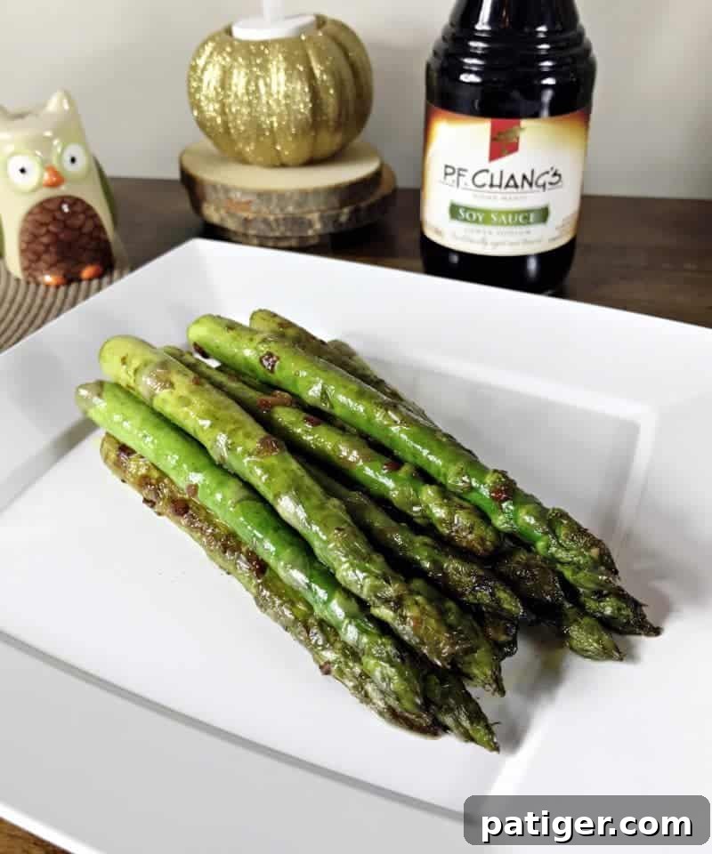 Garlic Soy Seared Asparagus 2 Pan seared asparagus with soy sauce and garlic on a plate with bottle of soy sauce behind it.