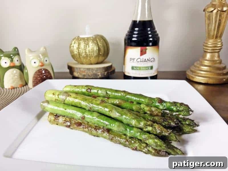 Garlic Soy Seared Asparagus 8 Pan seared asparagus with garlic and soy sauce served on white plate with bottle of P.F.Chang's Soy Sauce in the background.