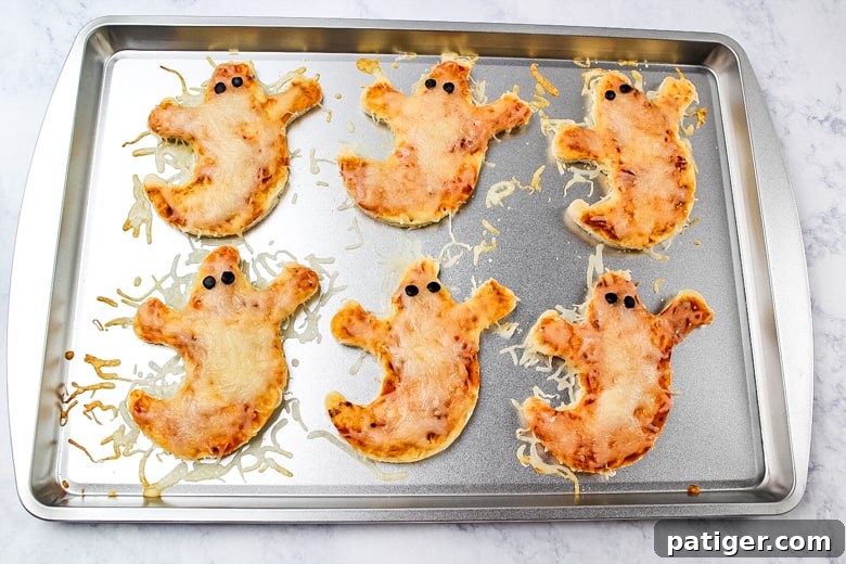 Phantom Pizza Bites 8 Ghost Pizzas on baking sheet fresh from the oven with cheese melted.