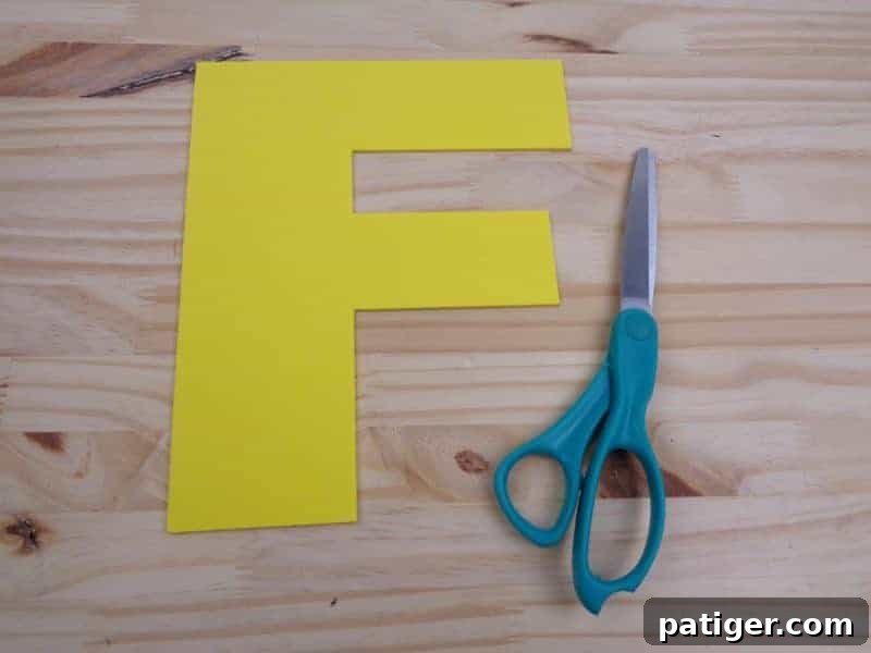 Cutting the traced letter F shape from craft foam, enhancing fine motor skills for young crafters.