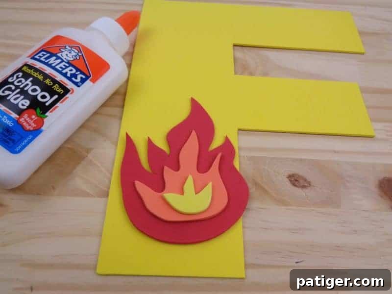 Carefully gluing the assembled fire pieces onto the craft foam letter F, creating a captivating F is for Fire craft.